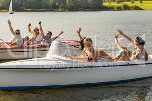 Waving friends sitting in motorboats summertime