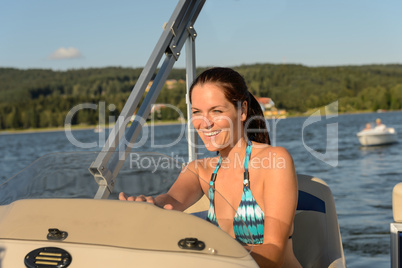 Cheerful woman navigating powerboat in summer