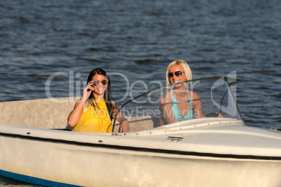 Young women in sunglasses sitting in motorboat