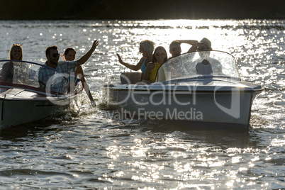 Silhouette of young friends in motorboats
