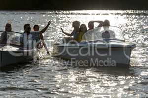 Silhouette of young friends in motorboats