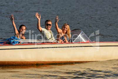 Young people waving from motorboat