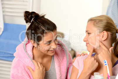 Teenage girls having acne problems in bathroom