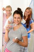 Teenage girl washing her teeth with friends