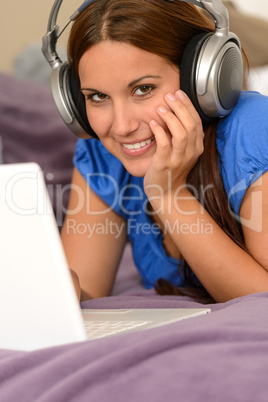 Young smiling girl using laptop with headphones