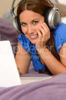 Young smiling girl using laptop with headphones