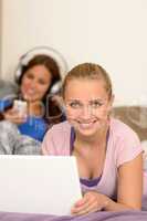 Smiling girls studying on laptop listening music