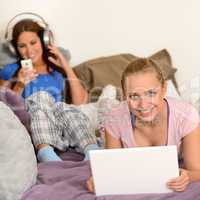 Girls lying bed with laptop and headphones