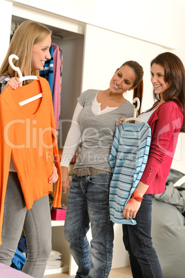 Three teenager girl choosing clothes from closet