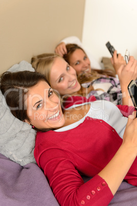 Three smiling young girl lying on bed