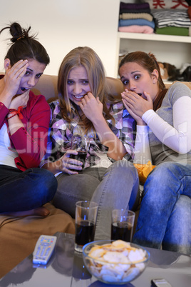 Scared girls watching horror movie on television