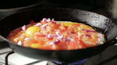 Egg frying in a pan. Adding onion slices.