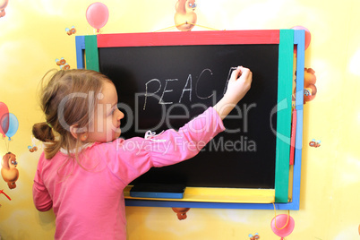 girl writes on blackboard word the peace