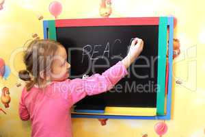 girl writes on blackboard word the peace
