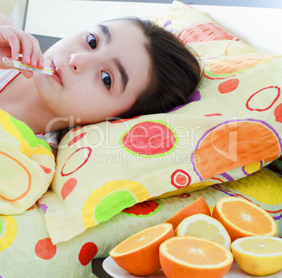 Sick little girl with a thermometer in bed