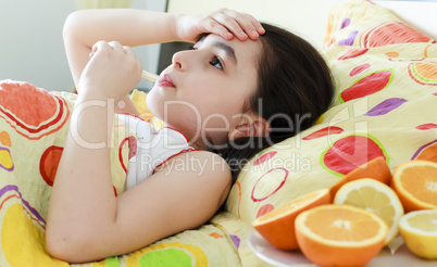 Little girl with a thermometer in bed