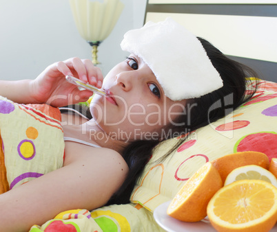 Sick young girl with a thermometer in bed