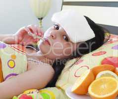 Sick young girl with a thermometer in bed