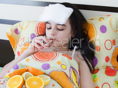 Sick young girl in bed with thermometer