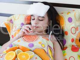 Sick young girl in bed with thermometer