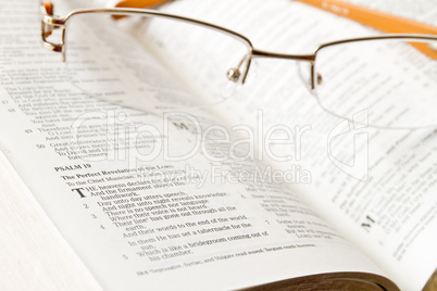 Holy Bible opened with glasses on it