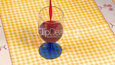 Red wine pouring in cup on table
