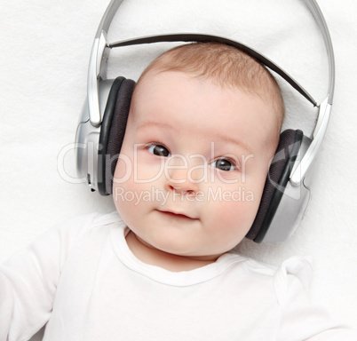 baby with headphone lies on back