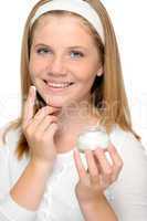 Cheerful young girl applying moistuizer face cream