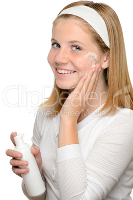 Teenager girl smiling applying moisturizer lotion face