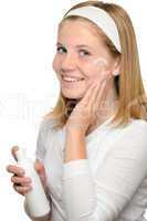 Teenager girl smiling applying moisturizer lotion face