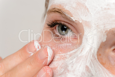 Young girl fingers applying face mask moisturizer