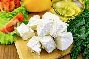 Feta cheese on the board with vegetables and oil