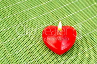 Heart of red candles on bamboo