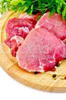 Meat slices on a round plate with greens