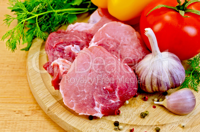 Meat slices on a wooden board with vegetables