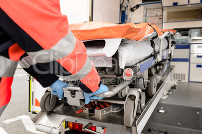 Paramedic pulling out gurney from ambulance car