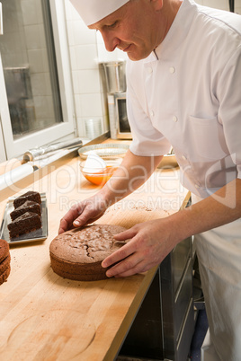 Middle aged cook placing cake in kitchen