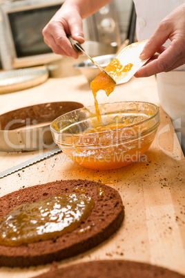 Chef pouring apricot jam to glass bowl