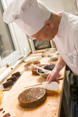 Male chef spreading apricot marmalade on cake