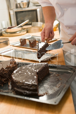Confectioner cutting a slice of chocolate cake