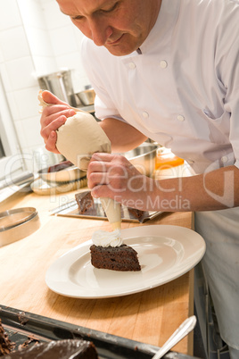 Pastry chef decorating cake with frosting