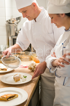 Male baker showing apprentice serving puff pastry