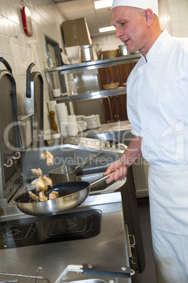 Male cook making chicken in frying pan