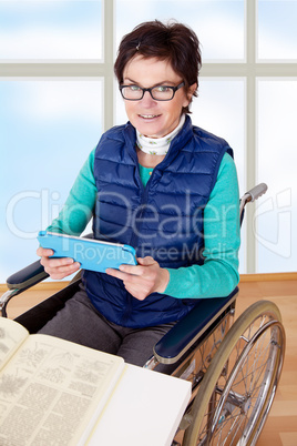 Woman with Tablet PC's in a wheelchair at the table