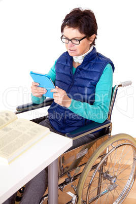 Woman with Tablet PC's in a wheelchair at the table