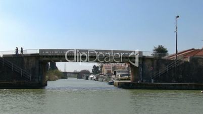 Vessel sails on the canal under the bridge in town