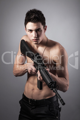 Handsome bare-chested soldier is holding a rifle