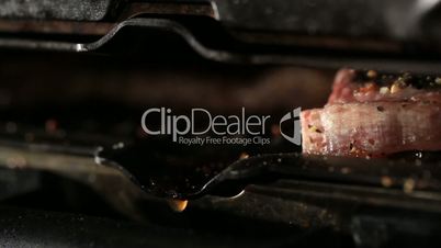 Pieces of meat are fried on the barbecue. Fat drops macro.