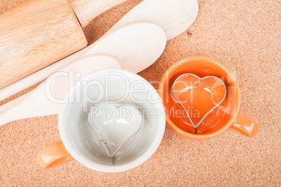 Ceramic cups with cookies cutter on cooking table