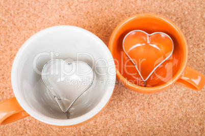 Ceramic cups with cookies cutter on cork background